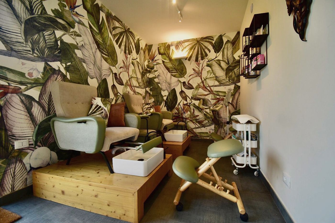 Le postazioni pedicure di Grace House, con poltrone verde salvia e carta da parati botanica